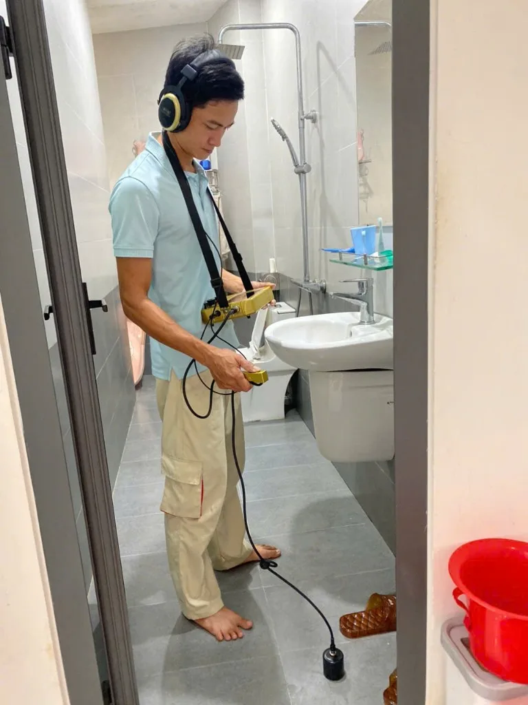 Thợ dùng thiết bị chuyên dụng kiểm tra rò rỉ nước dưới sàn nhà vệ sinh